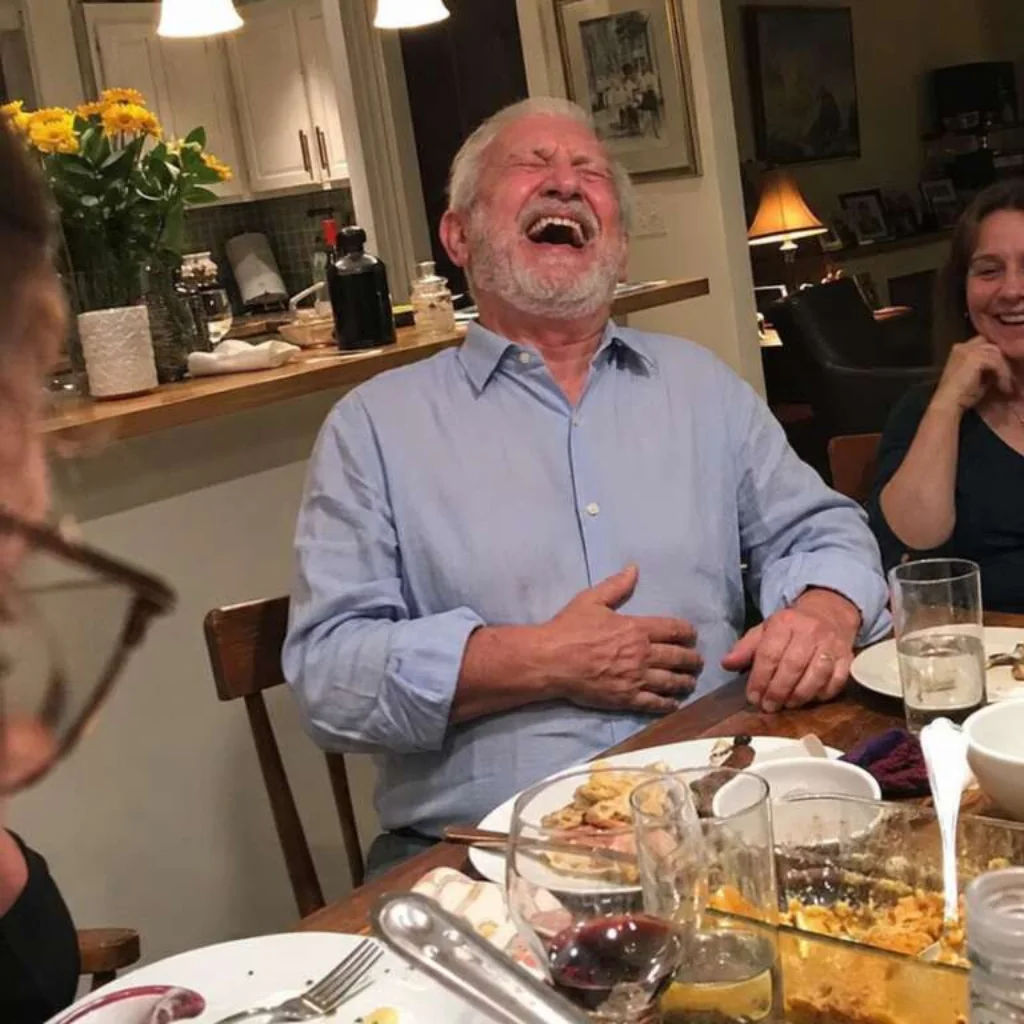 Oudere man lacht aan de eettafel
