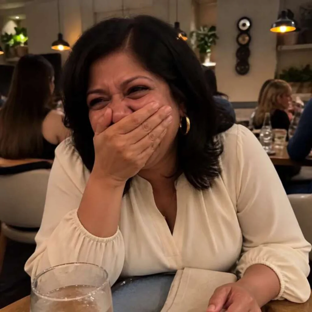 Vrouw lacht aan een tafel in een restaurant